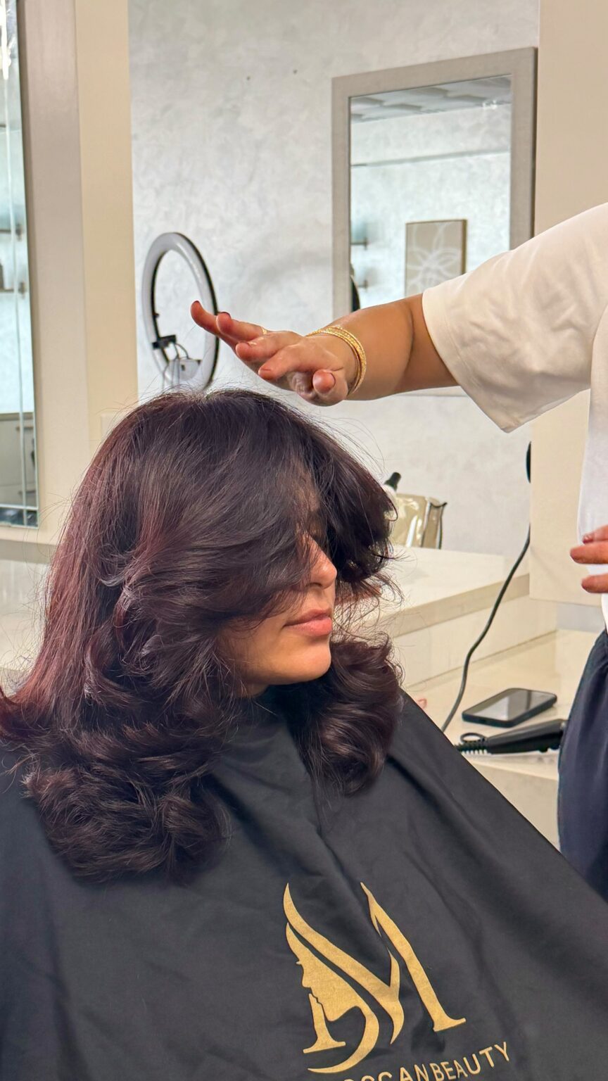 Stylist arranging long burgundy-toned layers in the Moroccan Beauty Center salon